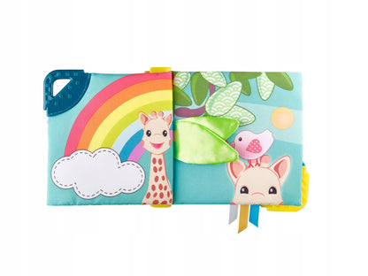 Otwarta książeczka Sophie la girafe z tęczą, żyrafą i zielonym materiałowym elementem.